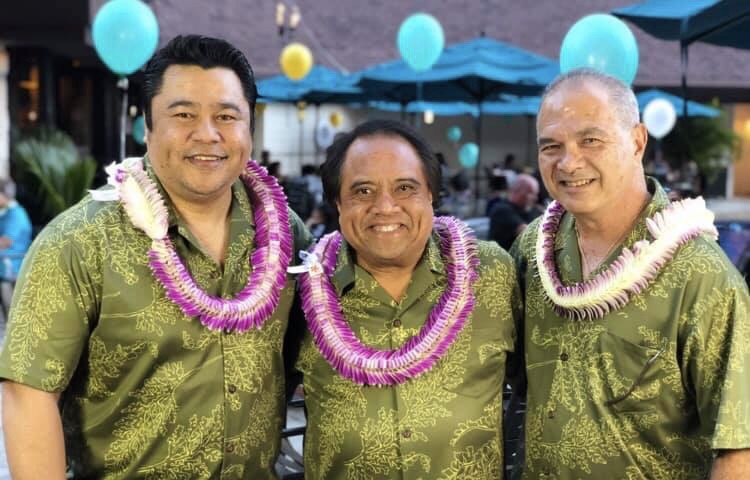 The three members of Hoʻokena, a Hawaiian music trio, posed together wearing lei